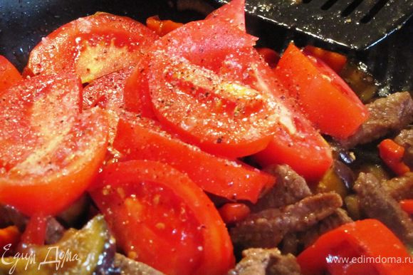 Через 3-5 минут добавляем нарезанный дольками помидор, дополнительно перчим, солим и перемешиваем.